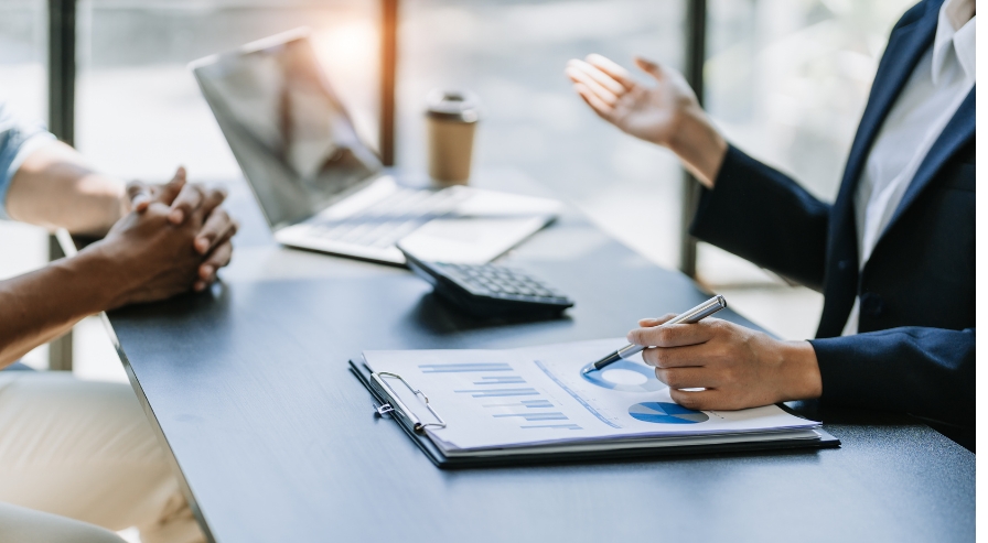 Two individuals discussing financial plans at a desk with charts, graphs, and a laptop, symbolizing expert guidance in SIP investments.