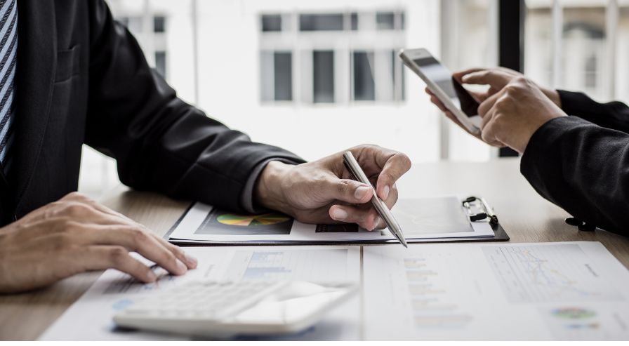 Two individuals discussing financial documents with charts and graphs, emphasizing the importance of choosing a financial advisor