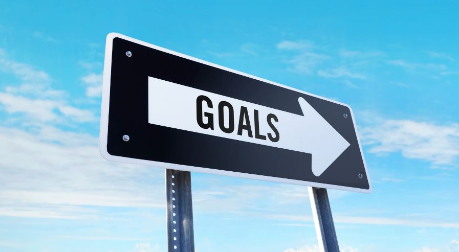 Road sign with 'GOALS' and an arrow pointing right against a blue sky, symbolizing direction and focus.