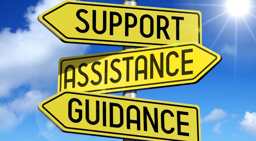 Three yellow directional signs reading 'SUPPORT,' 'ASSISTANCE,' and 'GUIDANCE' against a blue sky, symbolizing expert guidance for stress-free SIP investments.